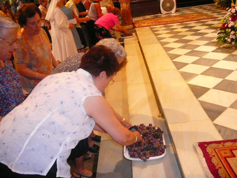 Los asistentes a la Santa Misa toman las uvas portadas por la Santa